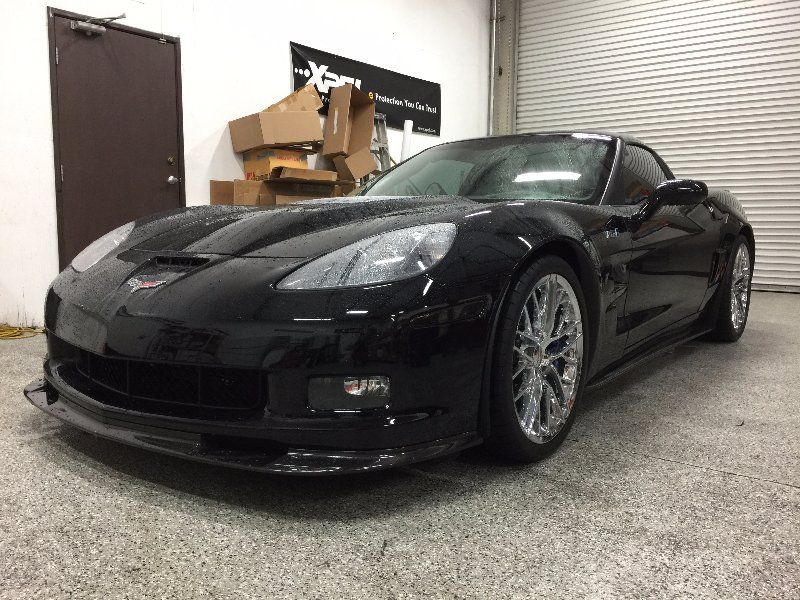 A black sports car is parked in a garage.
