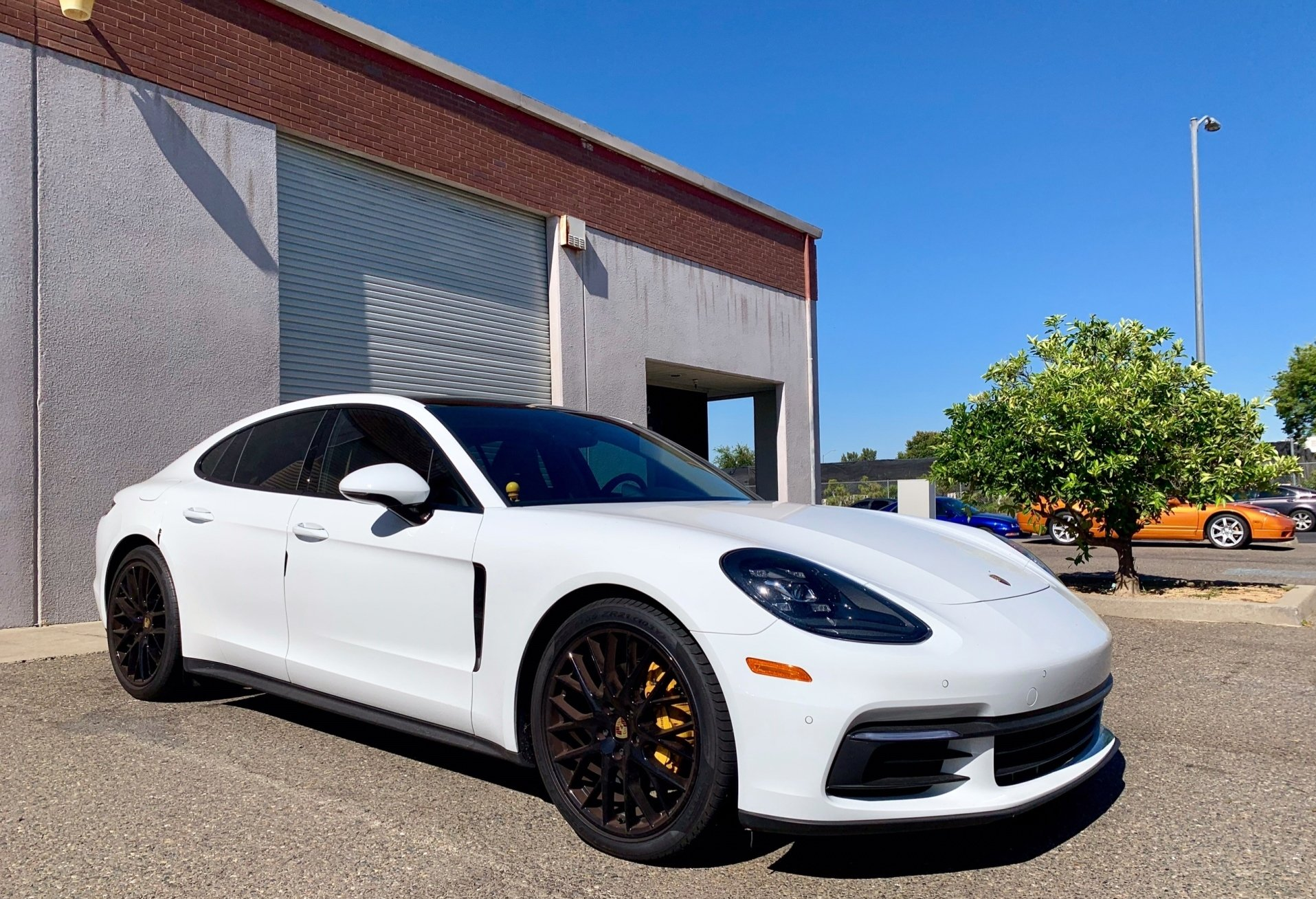 A white porsche panamera is parked in front of a building.