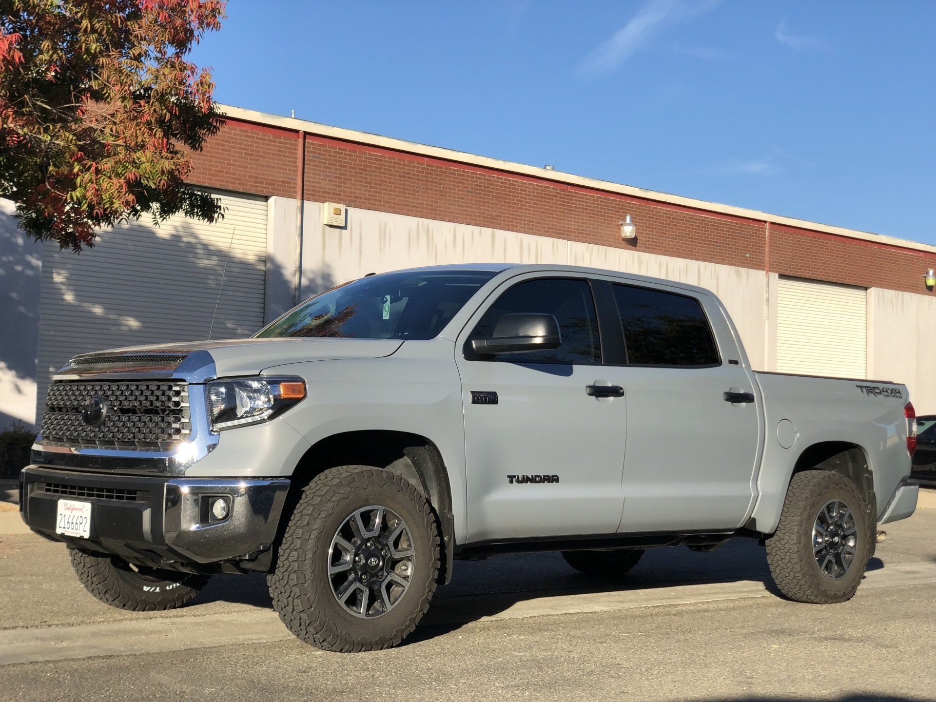 A silver toyota tundra truck is parked in front of a building.