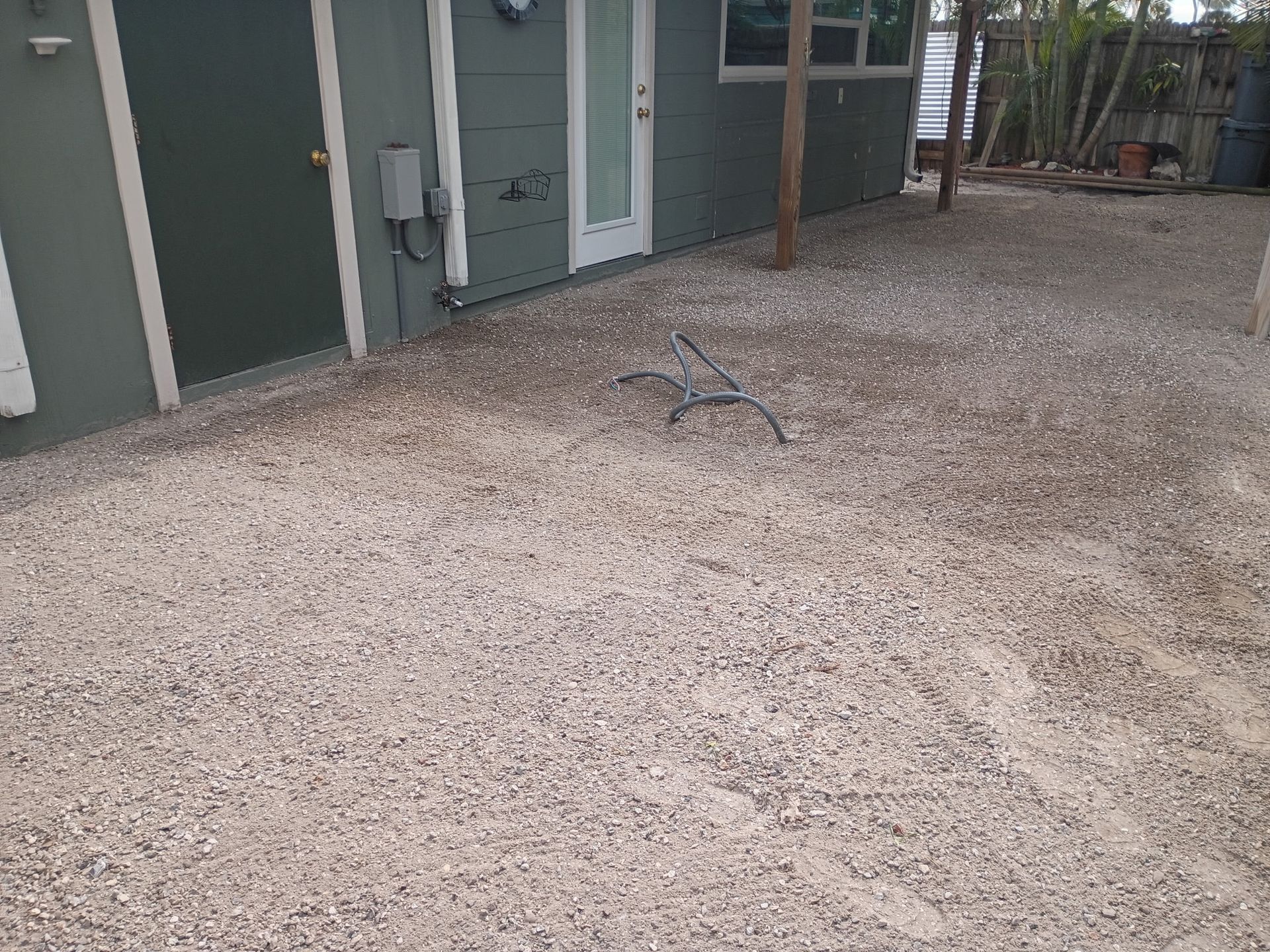 Gravel patio beside a building with a door and a bench.