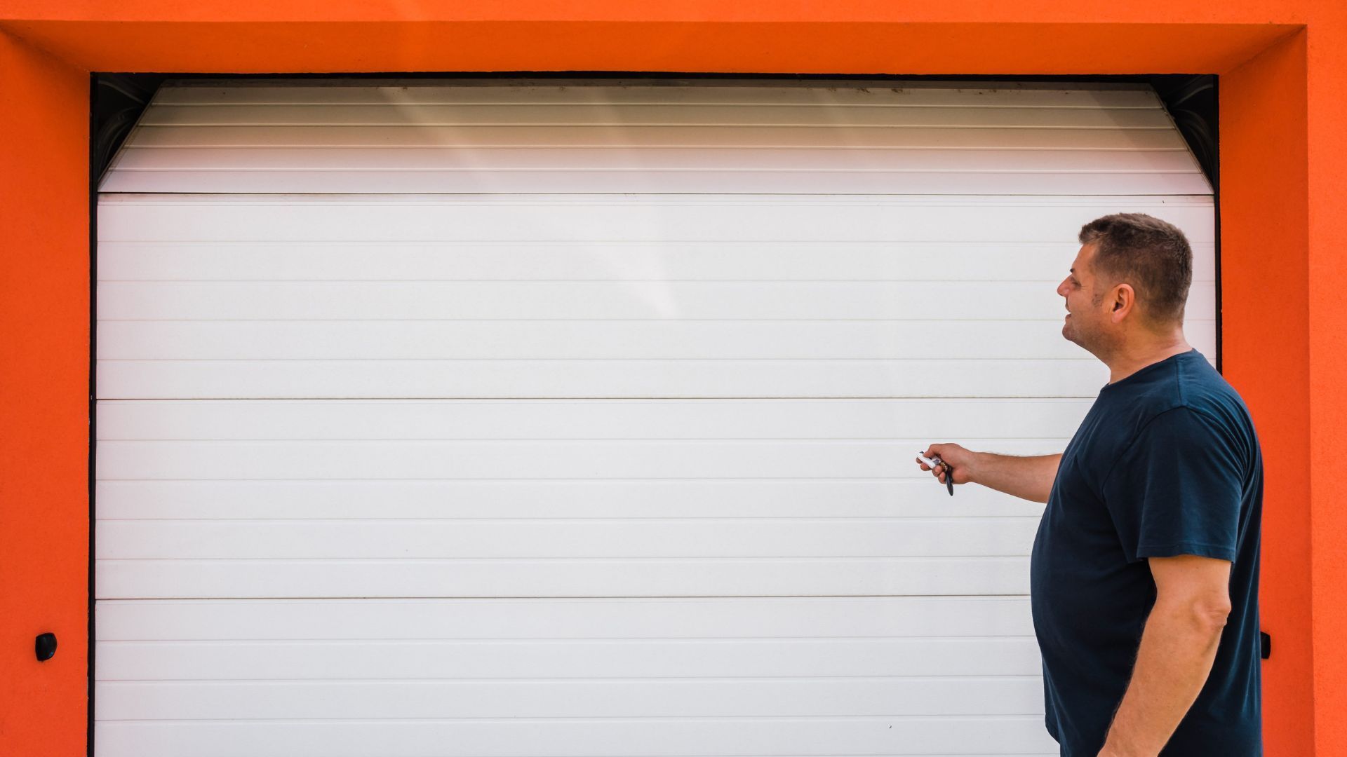 A man is opening a garage door with a key.