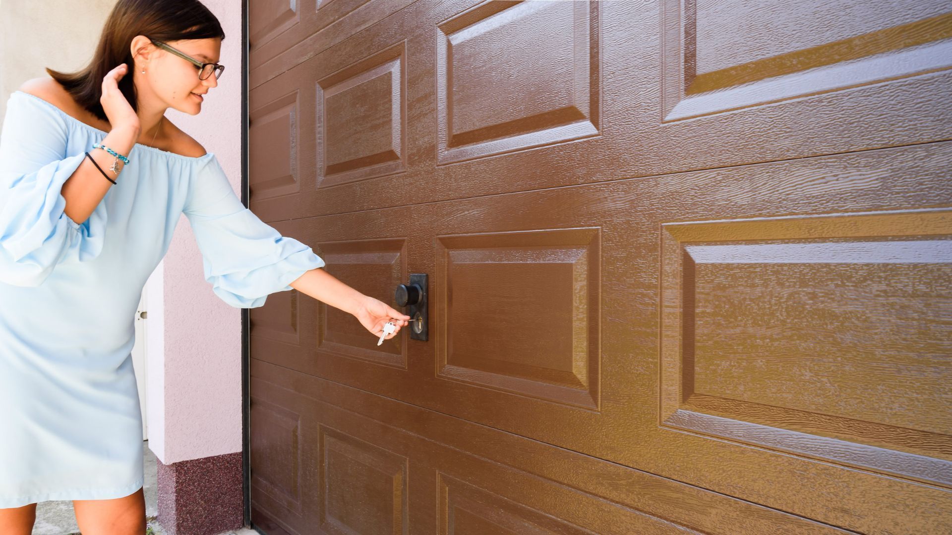 A woman is standing in front of a brown garage door.