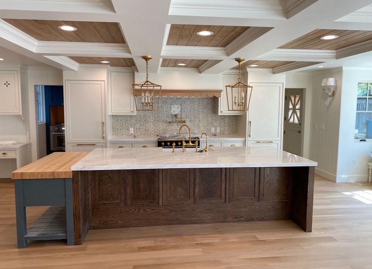 A modern kitchen with white cabinets , stools , and a large island.