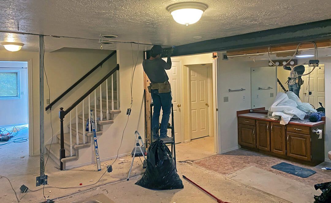 A man is standing on a ladder in a basement.