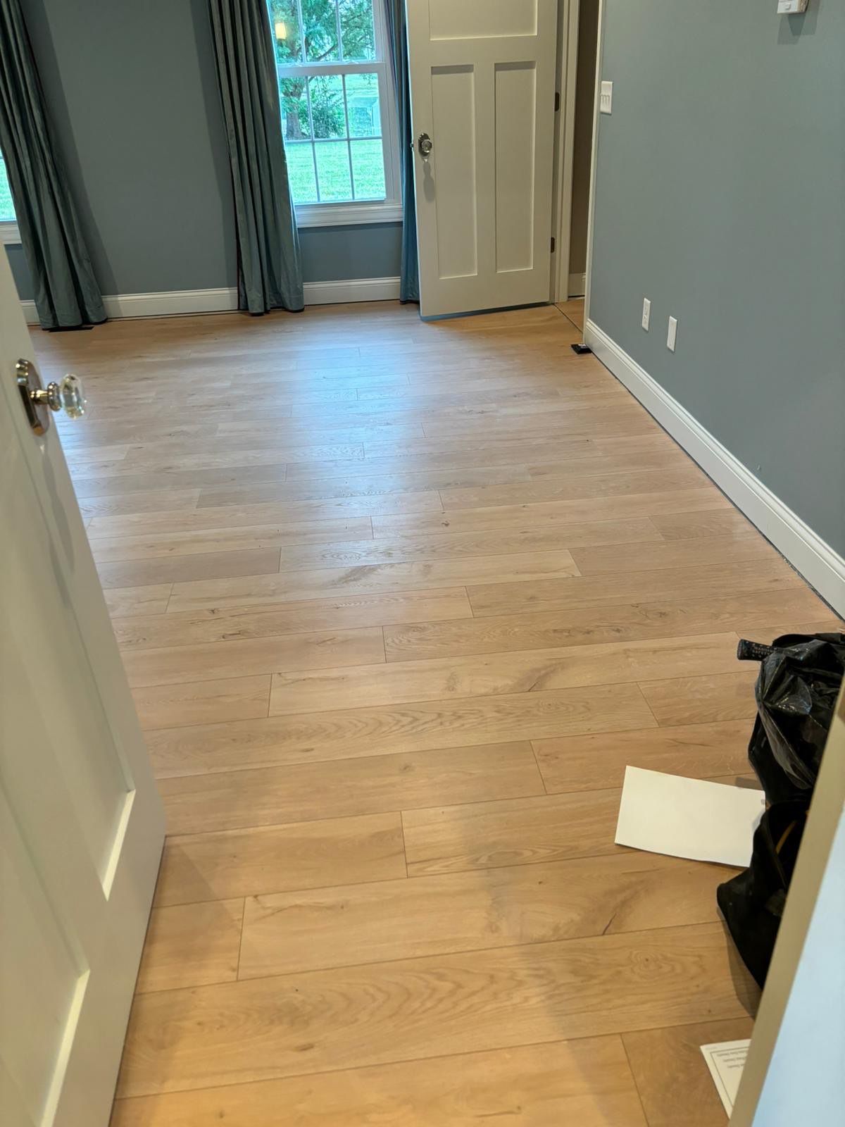 An empty room with hardwood floors and a window.