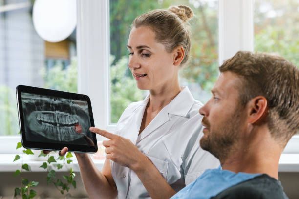 A dentist reviewing an X ray with a patient to explain an impacted wisdom tooth.