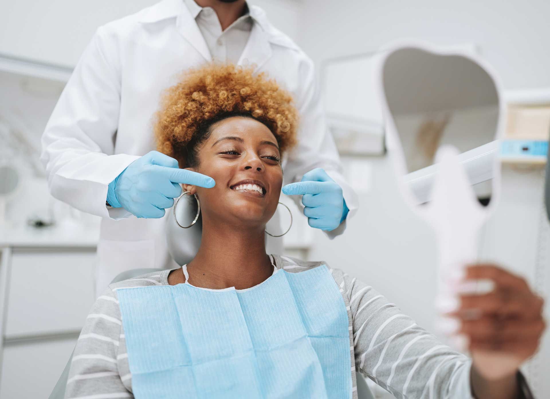 Dentist examining patient's teeth while patient holds a mirror. Dentist examining patient's teeth while patient holds a mirror.