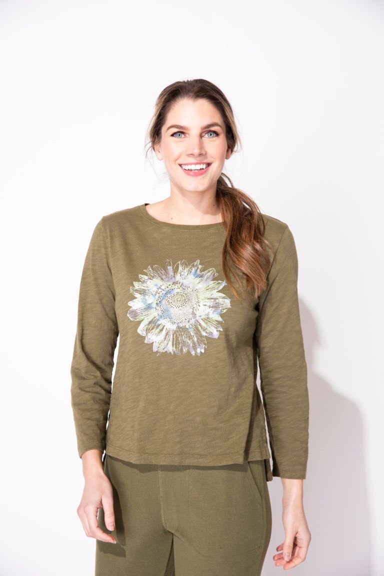 A woman wearing a green shirt with a flower on it