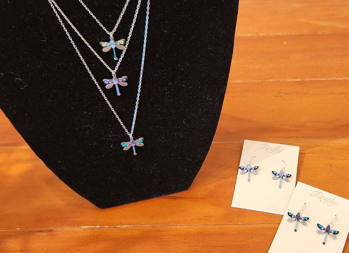 A dragonfly necklace and earrings are on display on a mannequin