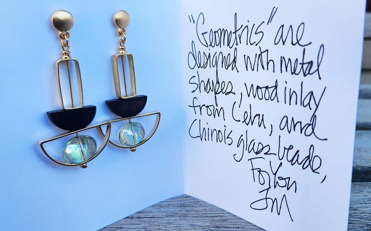 A pair of earrings sitting on top of a card that says ' handmade ' on it