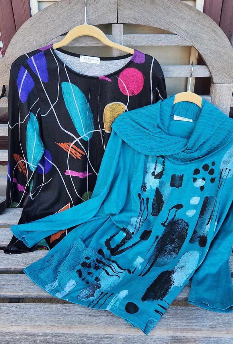 A black shirt and a blue shirt are sitting on a wooden bench