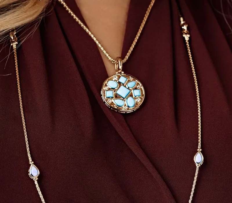 A woman wearing a gold necklace with a turquoise pendant