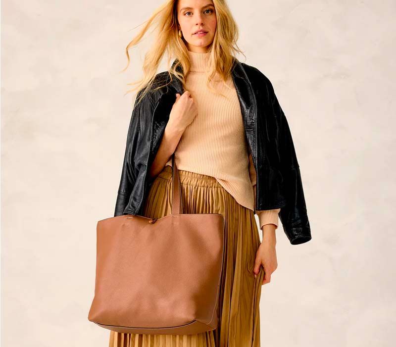 A woman wearing a black jacket and a brown tote bag