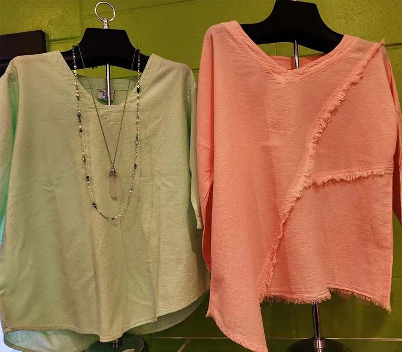 A green and a pink shirt are hanging on a hanger