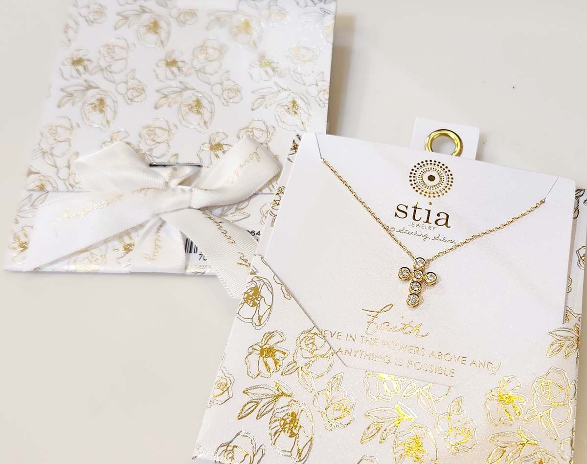 A necklace is in a white box with a gold bow