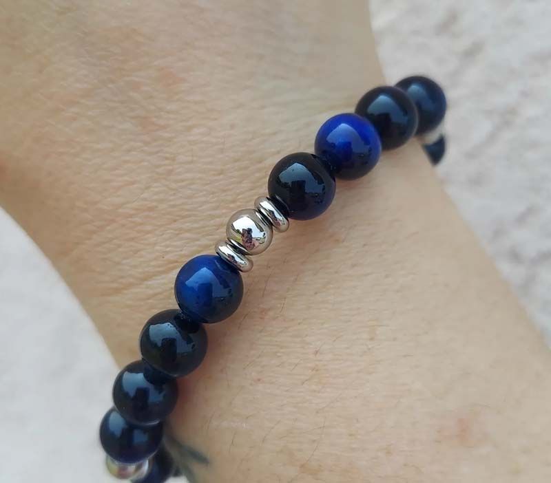 A person wearing a bracelet with blue and black beads
