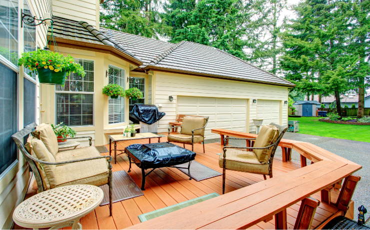 A photo of a patio built onto a house. The patio is medium-sized and is protected with a railing. The patio has lots of chairs plus a grill and a table.