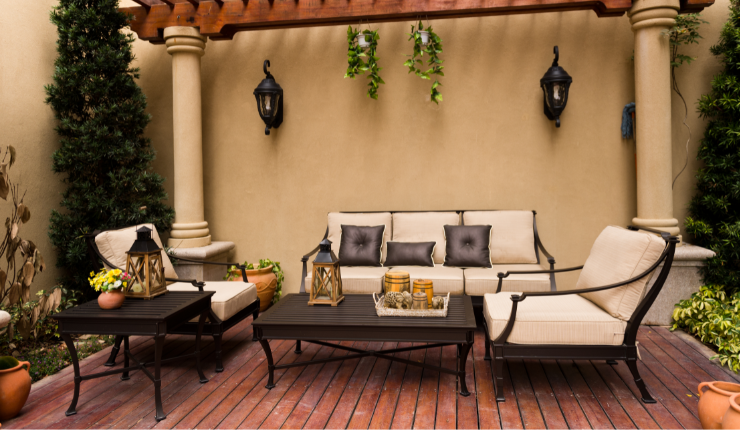 A photo of a patio in the backyard of a modern home in Buffalo, NY. The patio is dark brown, and the house is a light cream/beige. The patio furniture matches the color scheme of the backyard. Looks stunning