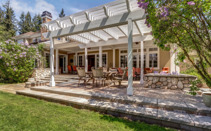 A photo of a large white pergola sitting on a patio in the backyard of a house in Buffalo, NY. Blue Buffalo Decks built the pergola.