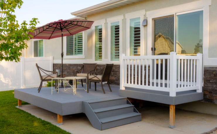 A photo of a small patio installed in the backyard of a small home in Buffalo, NY. The patio has a few chairs plus an umbrella to protect people from the sun.