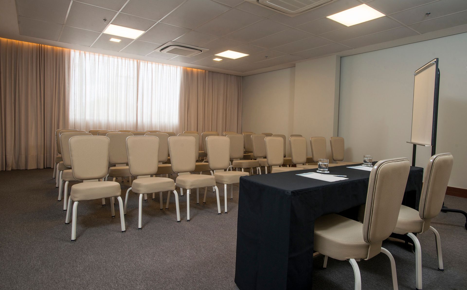 Uma sala de conferências com mesa e cadeiras preparadas para uma reunião.