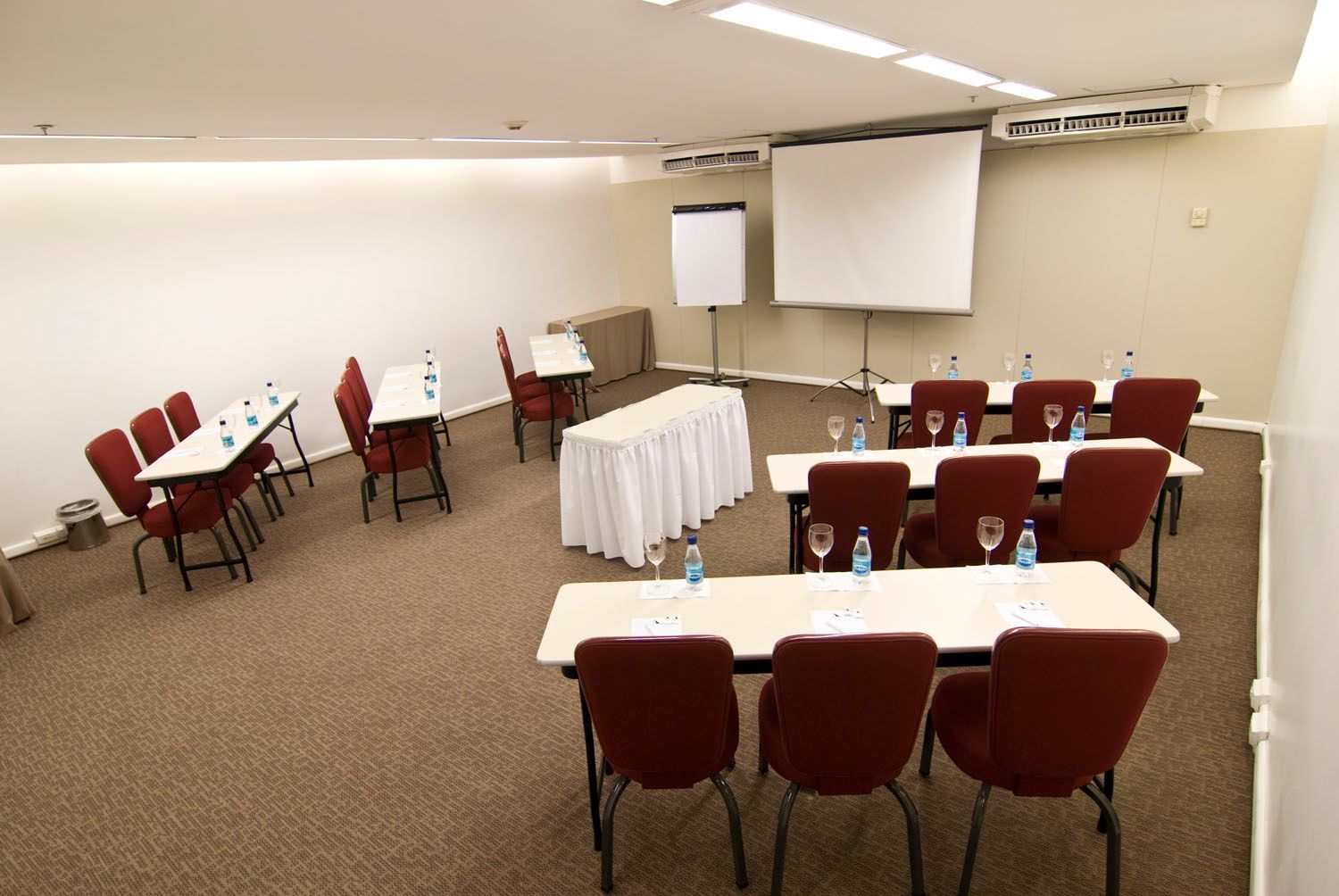 Uma sala de conferências com mesas e cadeiras e uma tela de projeção