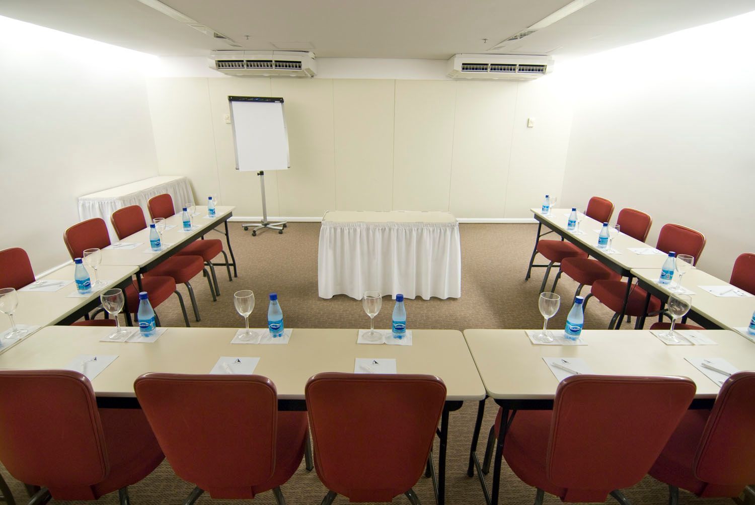 Uma sala de conferências com mesas e cadeiras preparadas para uma reunião.