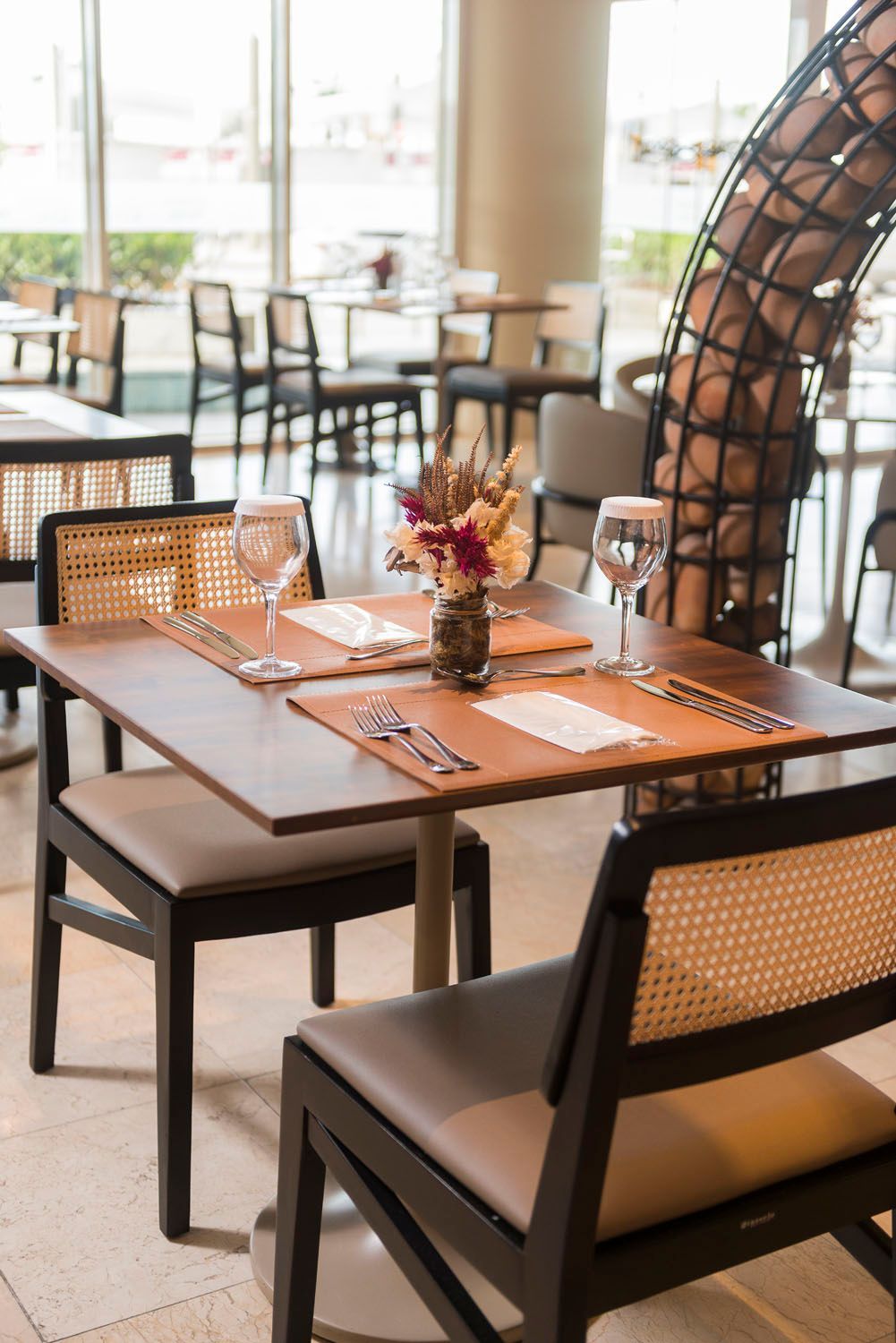 Um restaurante com mesas e cadeiras e um vaso de flores na mesa.