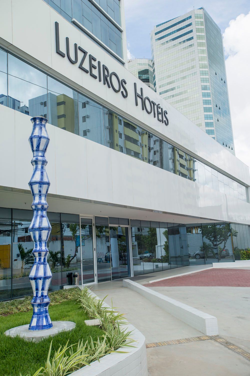 Uma escultura azul está em frente a um prédio que diz hotéis luzeiros