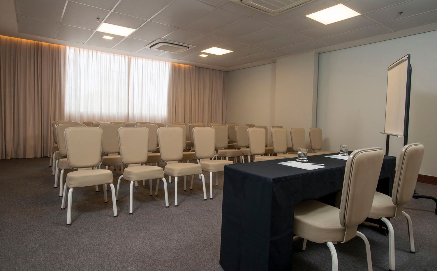 Uma sala de conferências com mesa e cadeiras enfileiradas.