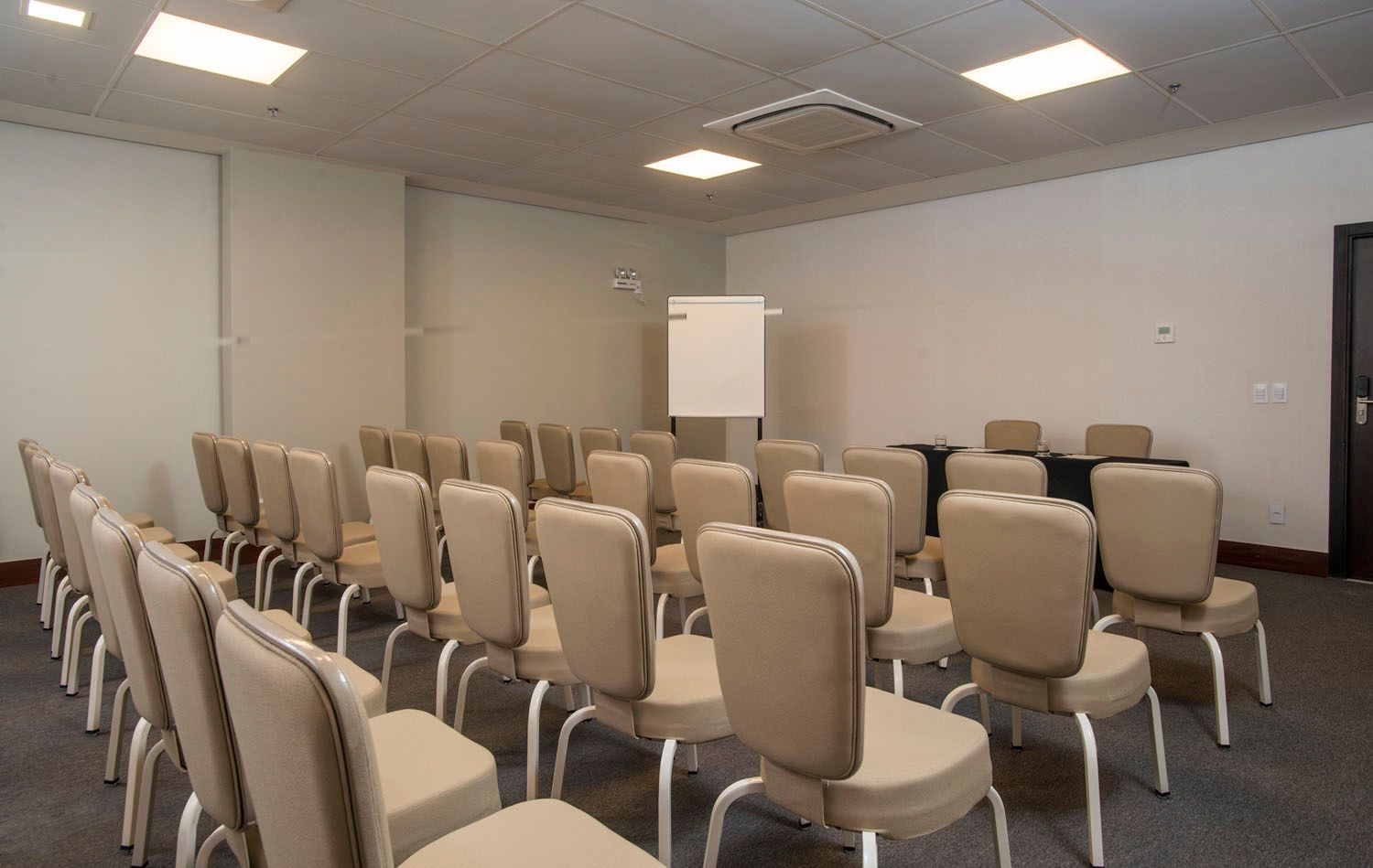 Uma sala de conferências com fileiras de cadeiras e um quadro branco