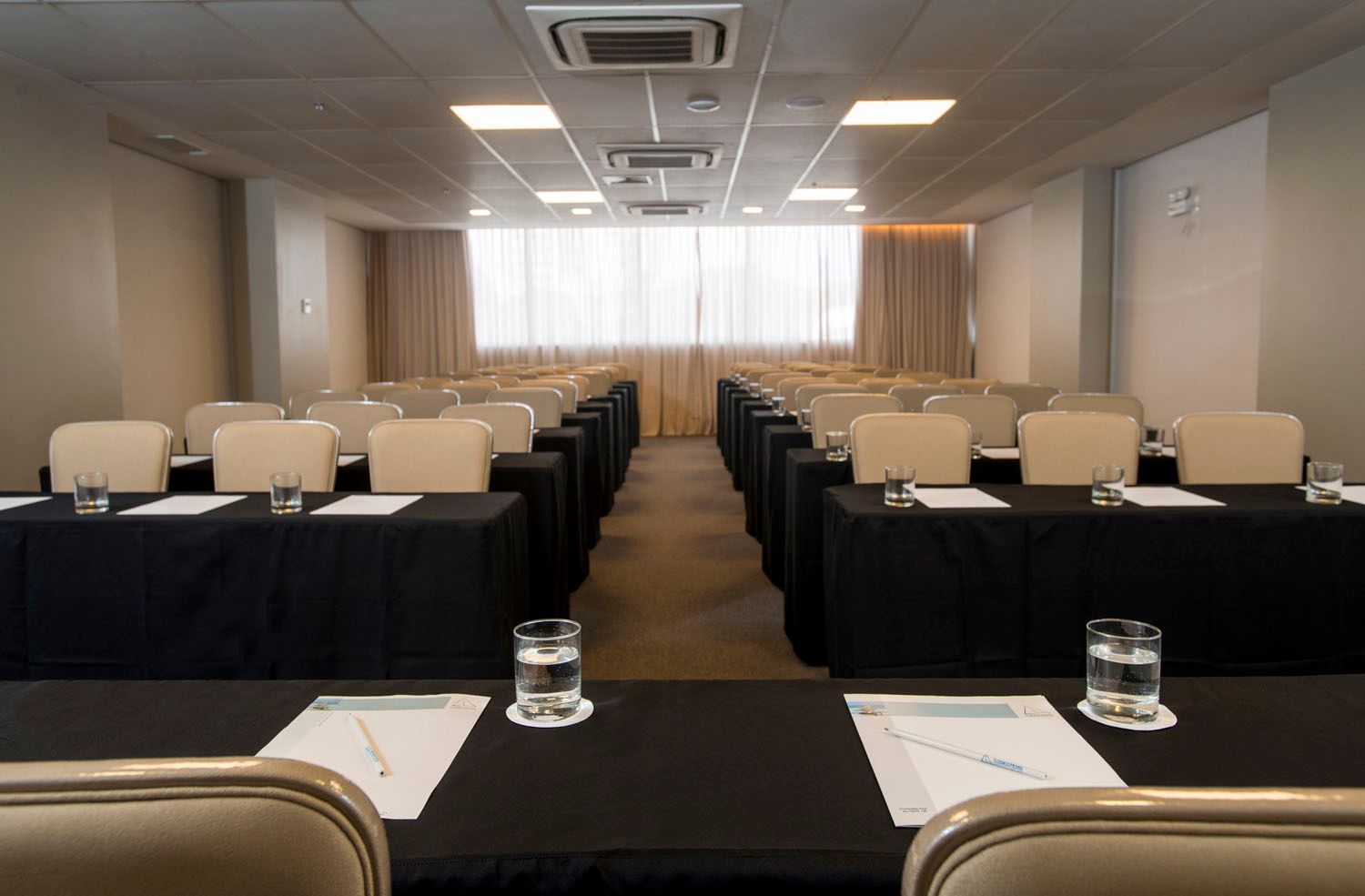 Uma sala de conferências com mesas e cadeiras preparadas para uma reunião.