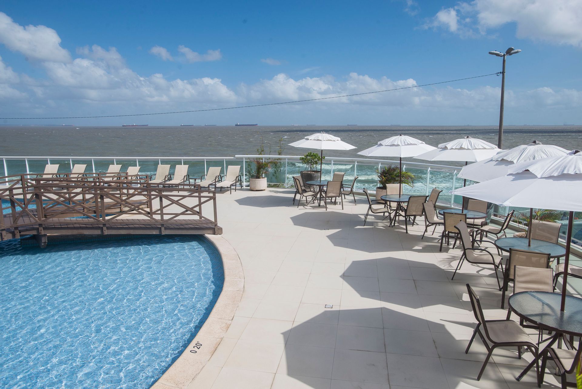 Uma grande piscina com mesas e cadeiras e guarda-sóis
