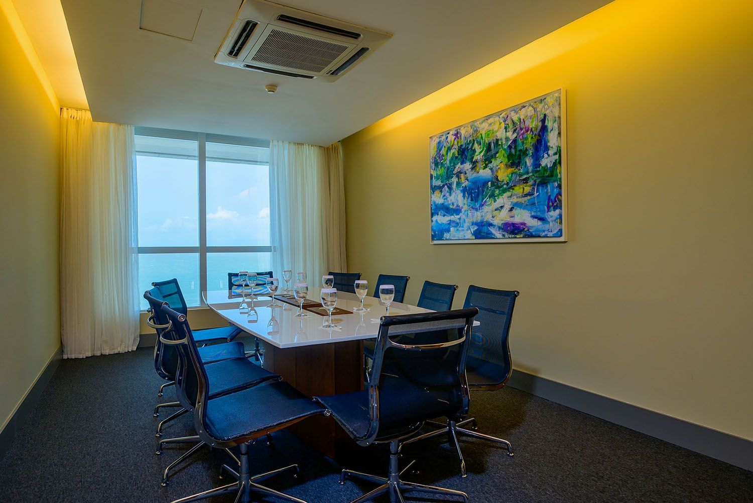 Uma sala de conferências com uma longa mesa e cadeiras e uma pintura na parede.