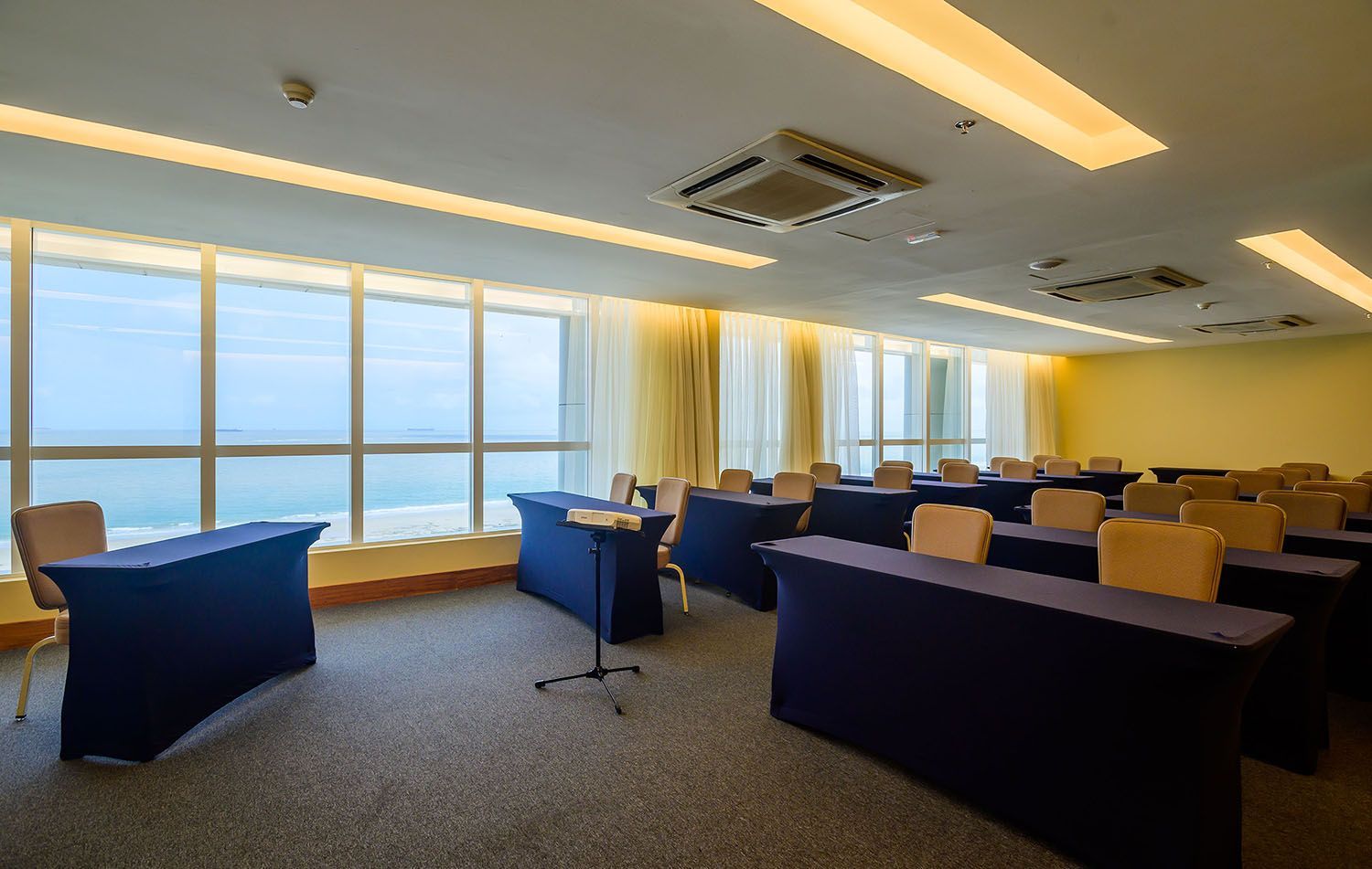 Uma sala de conferências com mesas e cadeiras e vista para o mar.