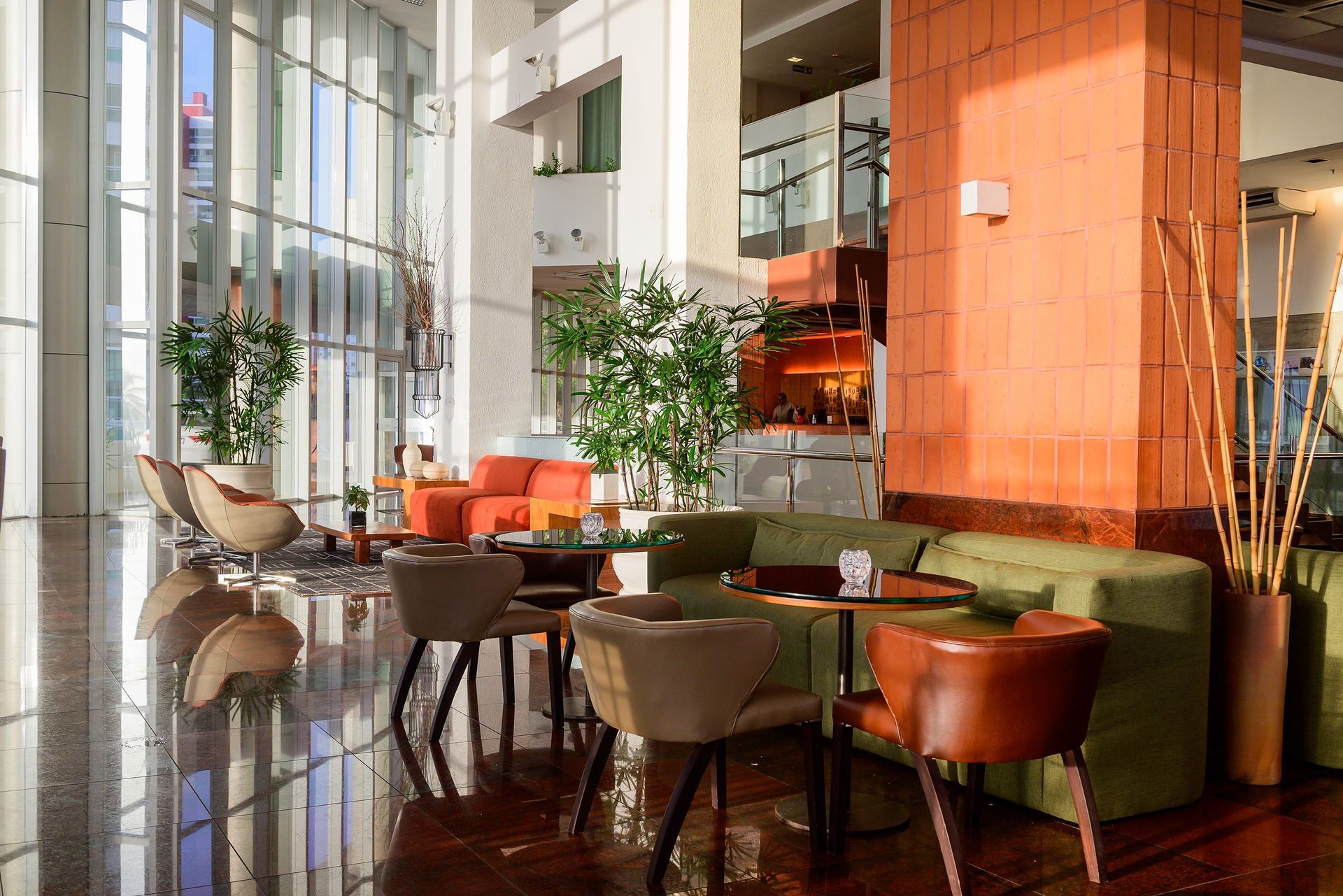 Um lobby de hotel com mesas e cadeiras e uma grande janela.