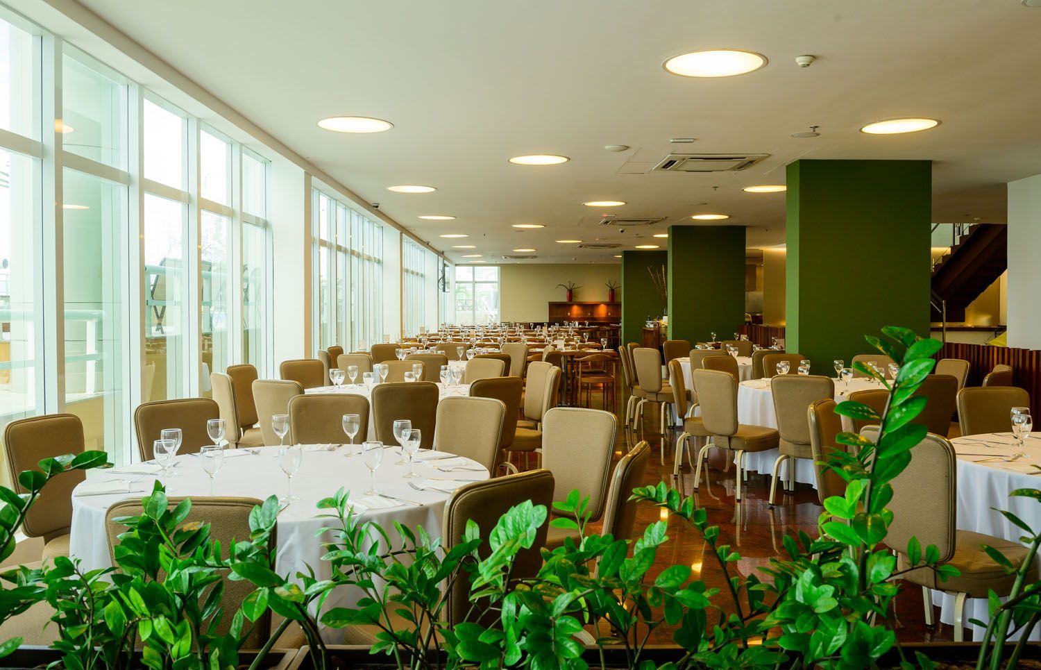Uma grande sala de jantar com mesas e cadeiras e muitas janelas.