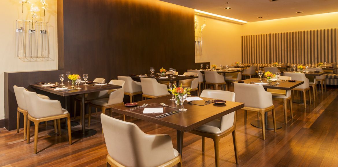 Um restaurante cheio de mesas e cadeiras e um lustre.