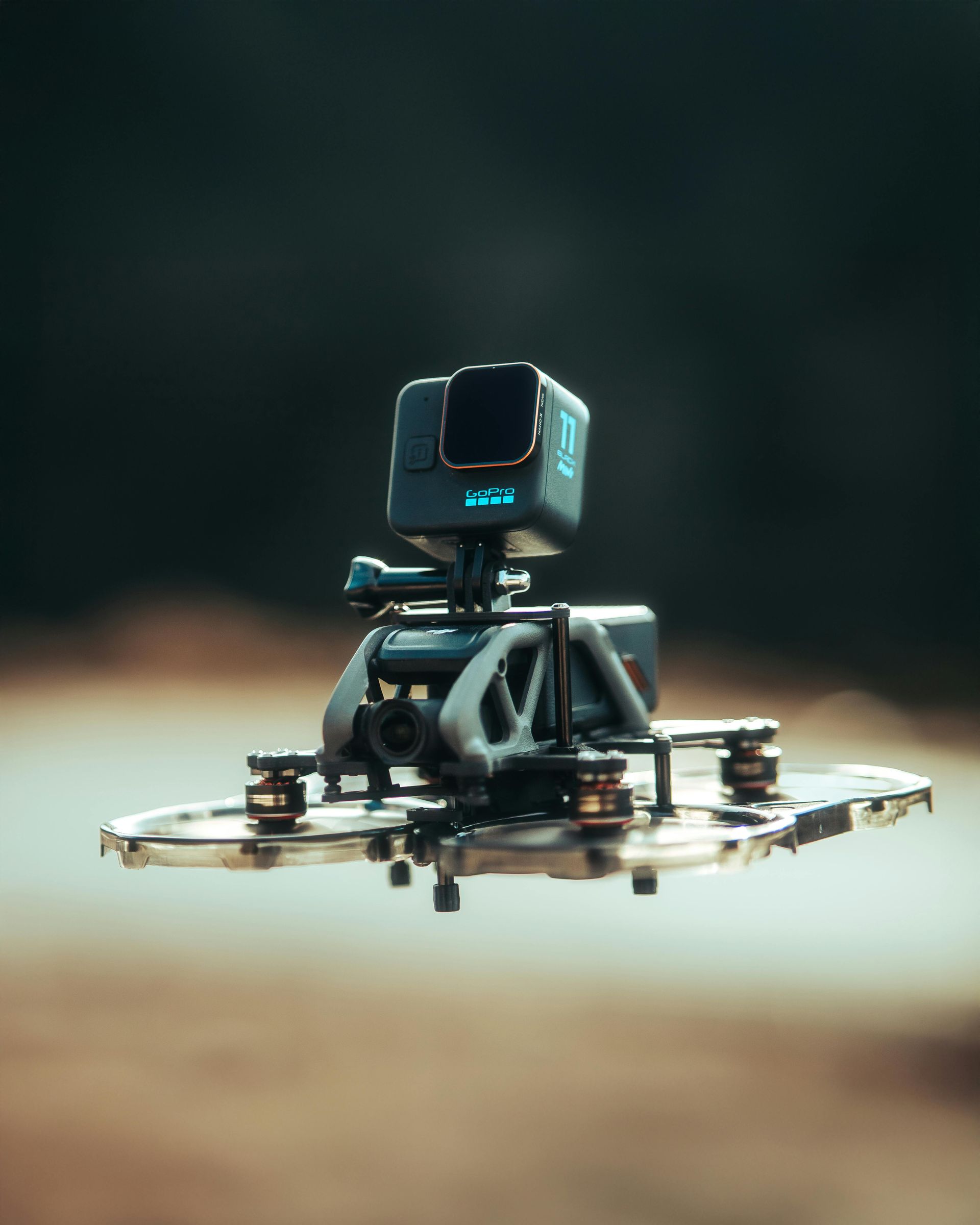 Small drone with a GoPro camera, hovering outdoors.