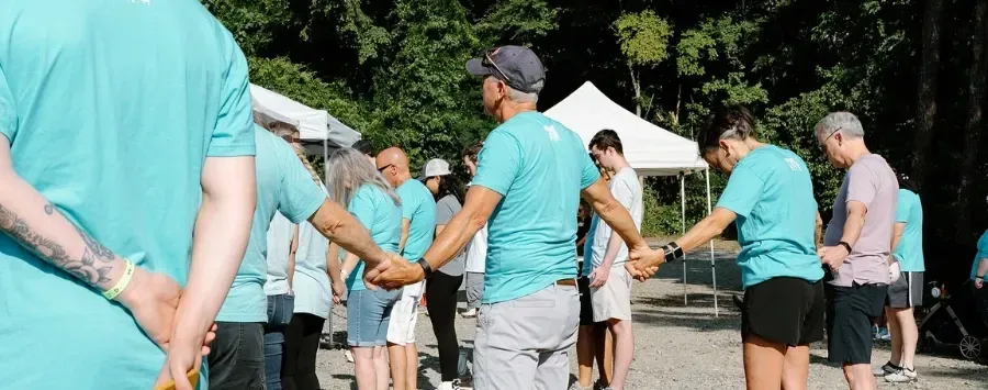 A group of people are standing in a circle holding hands.