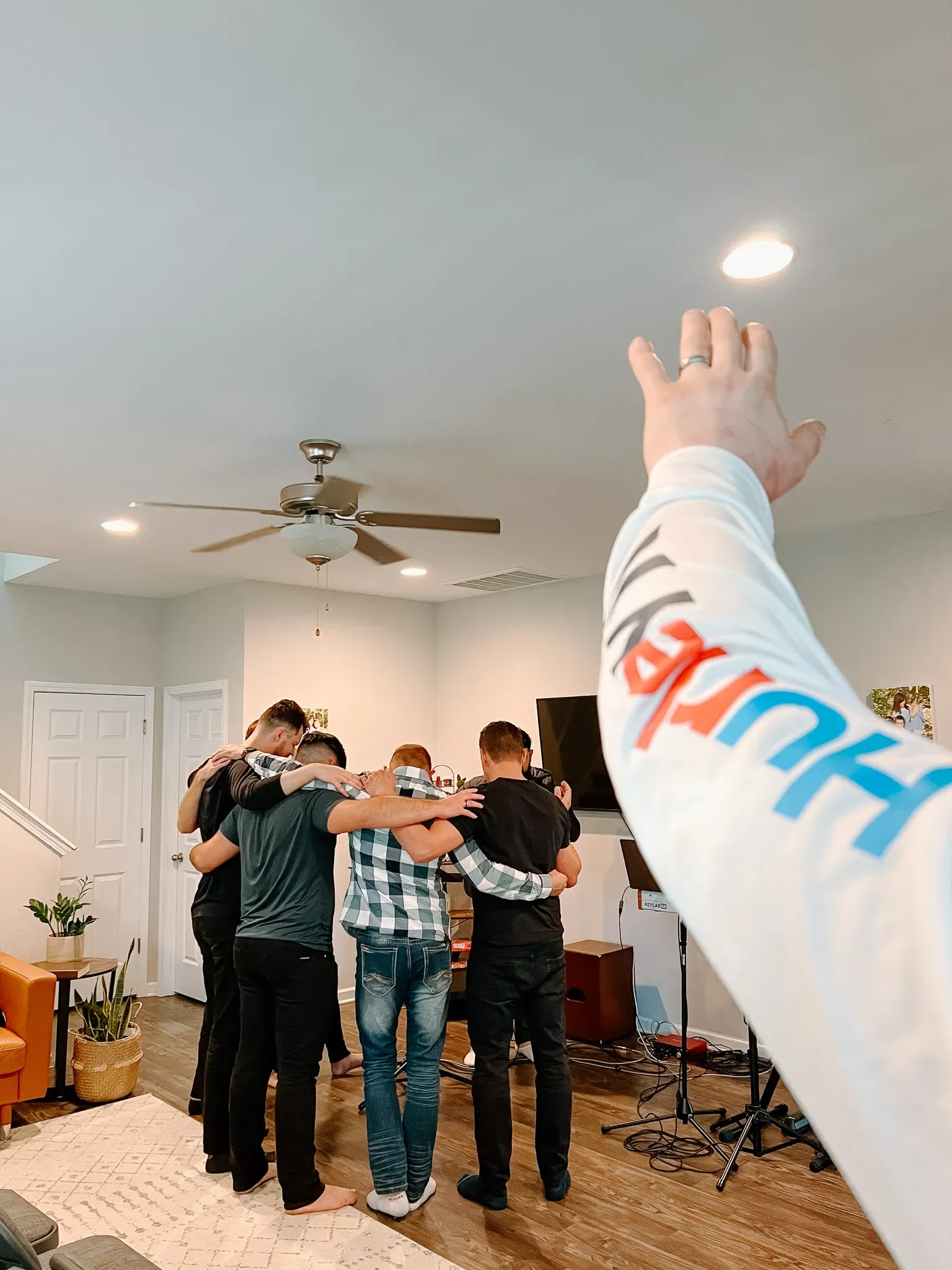 A group of men are standing in a living room with their arms around each other.