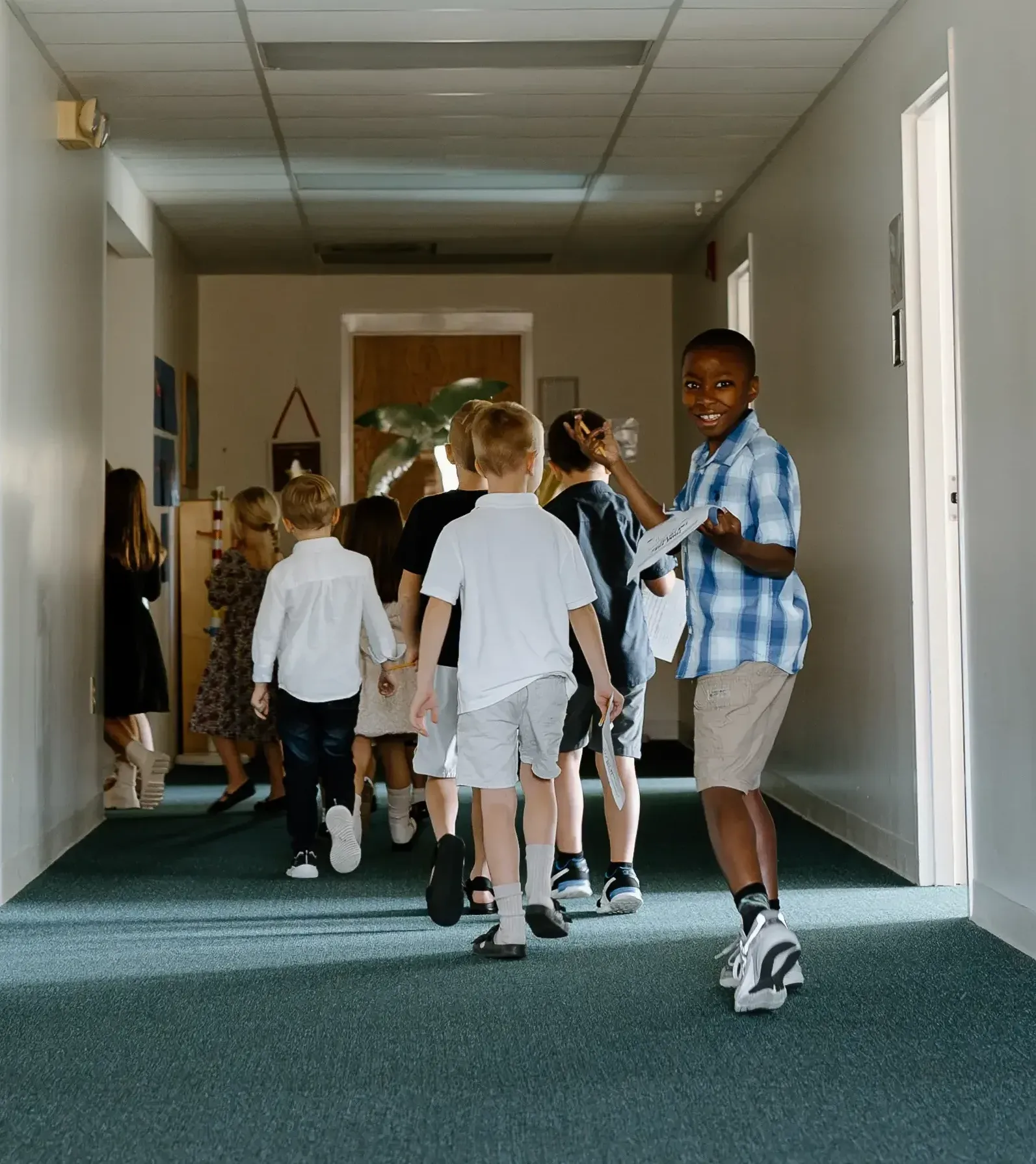 A group of children are walking down a hallway.