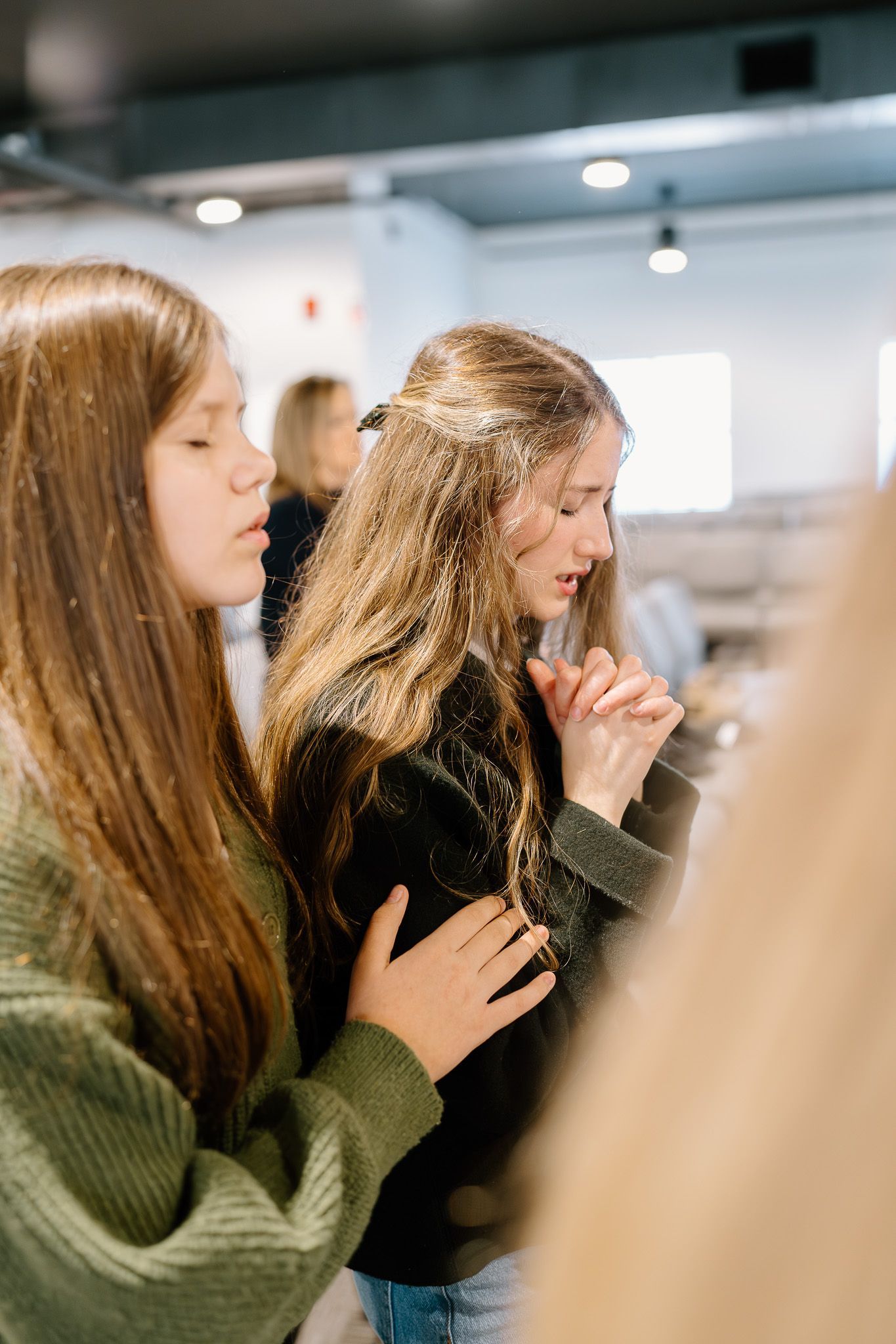 Two young women are praying together in a church.