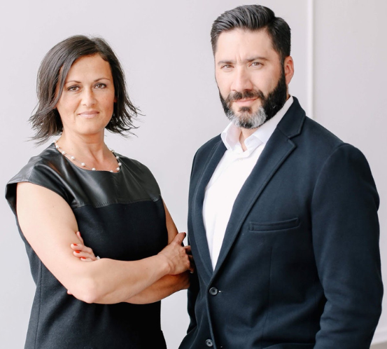 A man and a woman standing next to each other with their arms crossed