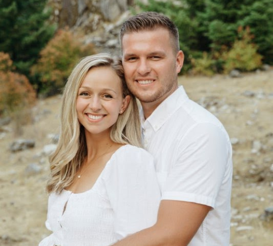 A man and a woman are posing for a picture in a field.