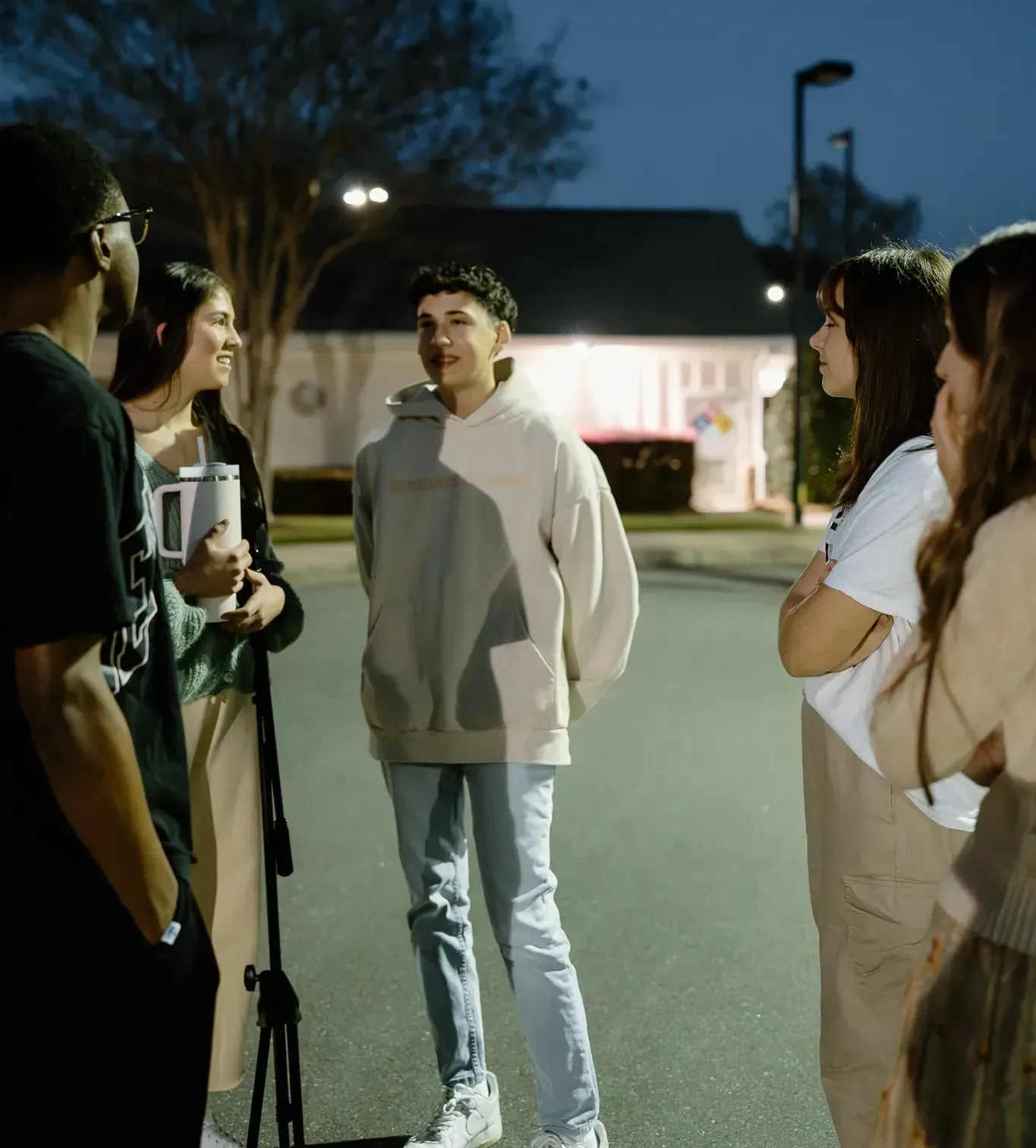 A group of people standing on a street talking to each other
