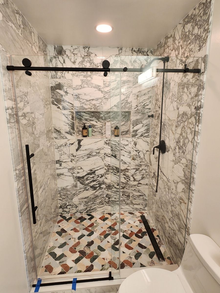 Glass shower enclosure with white tile