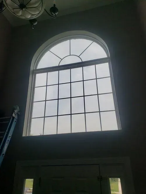 A large window in a room with a ladder in the background.
