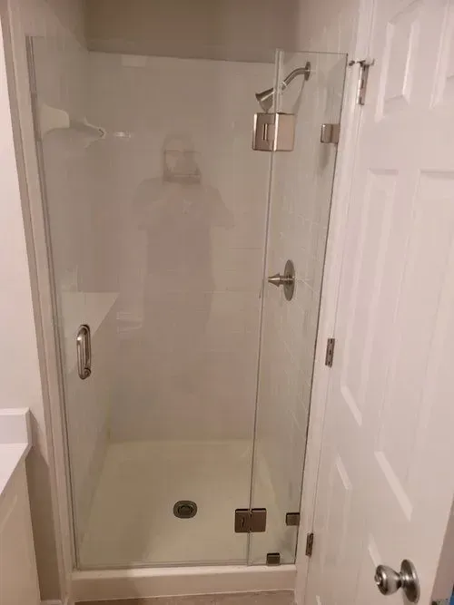 A bathroom with a walk in shower with a glass door.