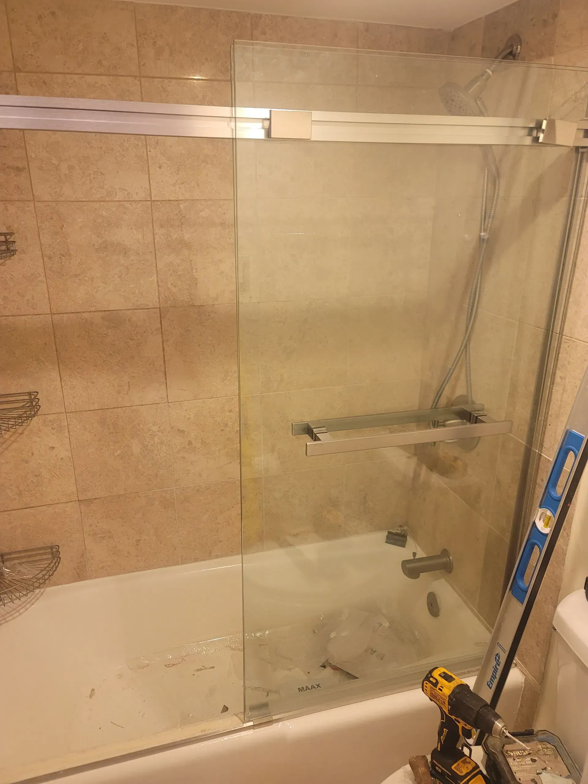 A bathroom with a bathtub and a shower door being installed.